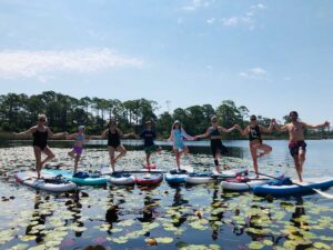 Group of adults and kids doing yoga on paddleboards