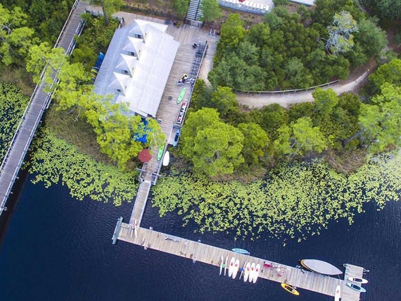 Aerial view of boat house club, pool, building, dock, kayaks and paddleboards